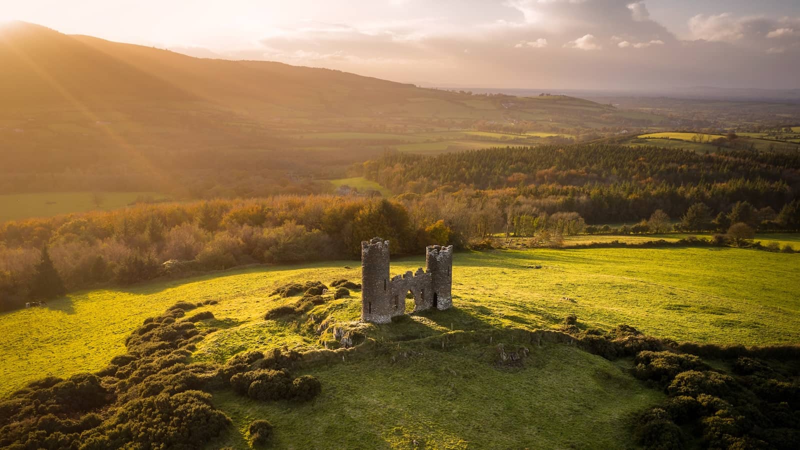 Aerial view of a historic stone tower house in the Ballyhoura countryside at sunset in County Limerick.