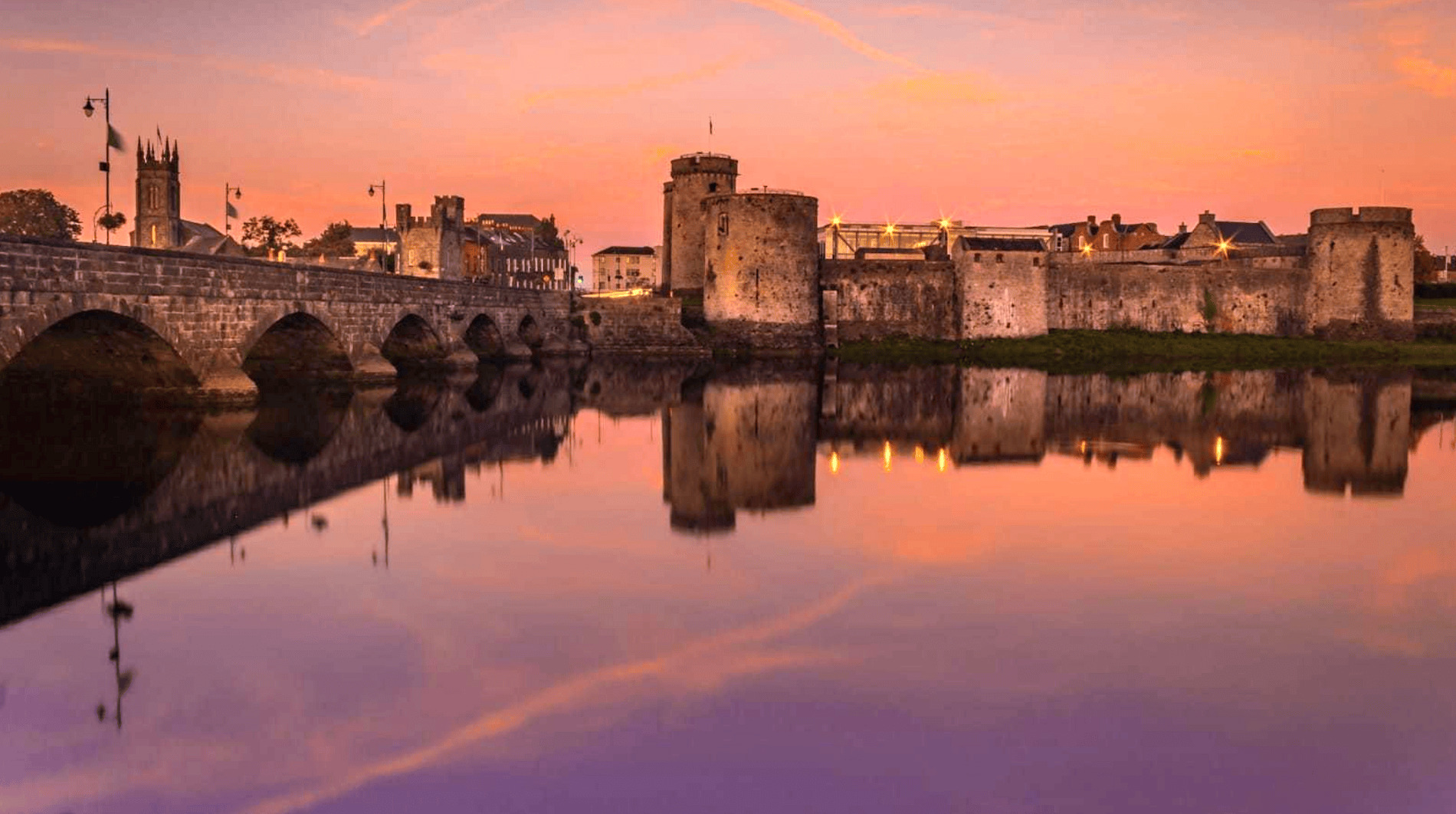 King John’s Castle and Thomond Bridge reflected in the River Shannon at sunset in Limerick city.