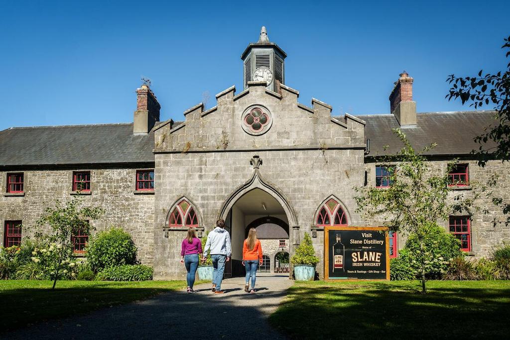 Visitors walking towards the stone entrance of Slane Distillery, Boyne Valley, County Meath, on a sunny day.