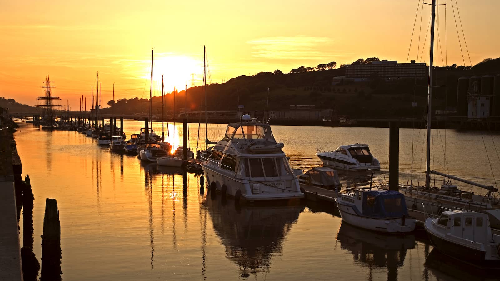 Boats moored along the River Suir in Waterford City at sunset with golden reflections on the water.