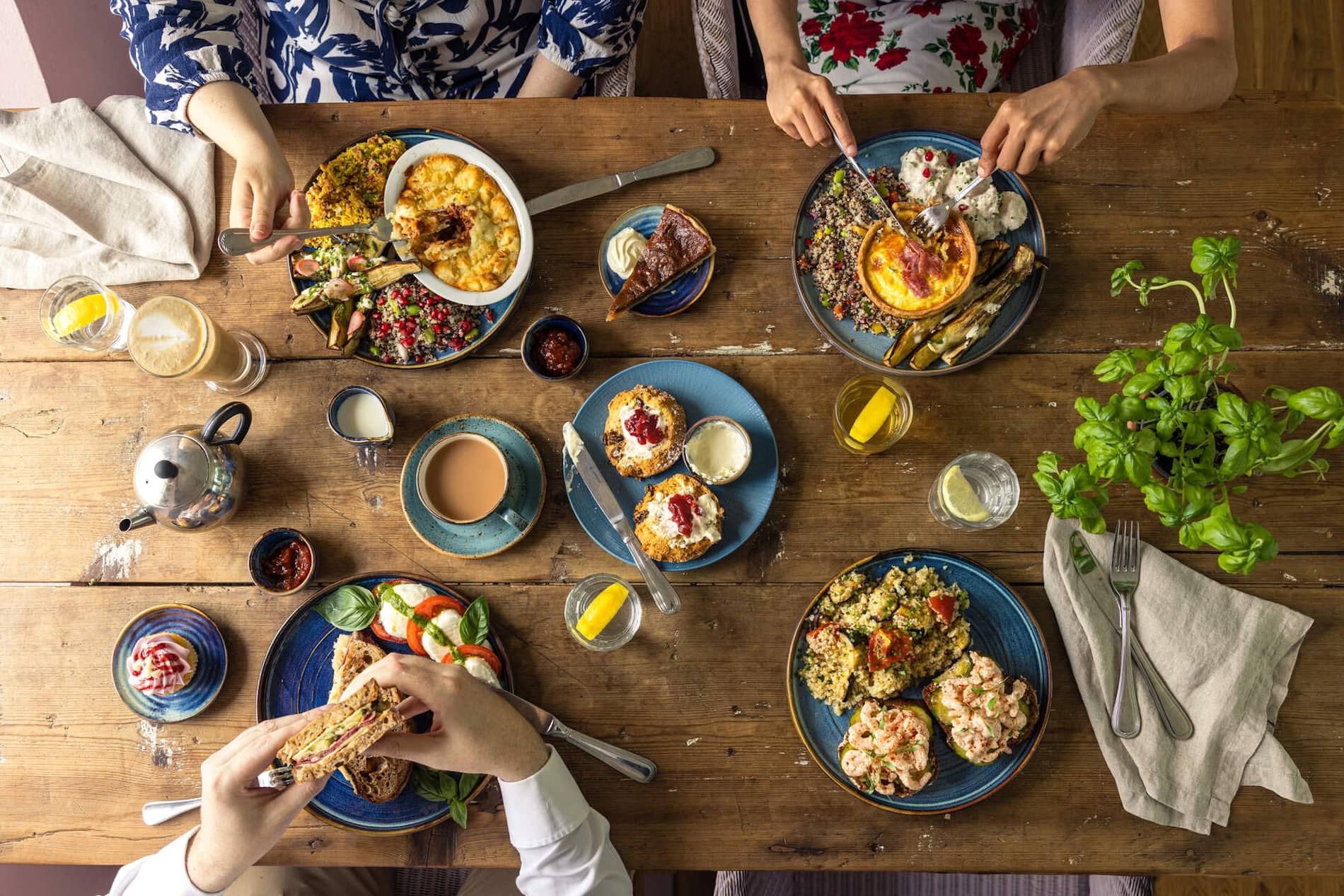 People enjoying brunch and coffee around a table filled with colourful dishes and desserts in Mount Congreve Gardens, County Waterford.