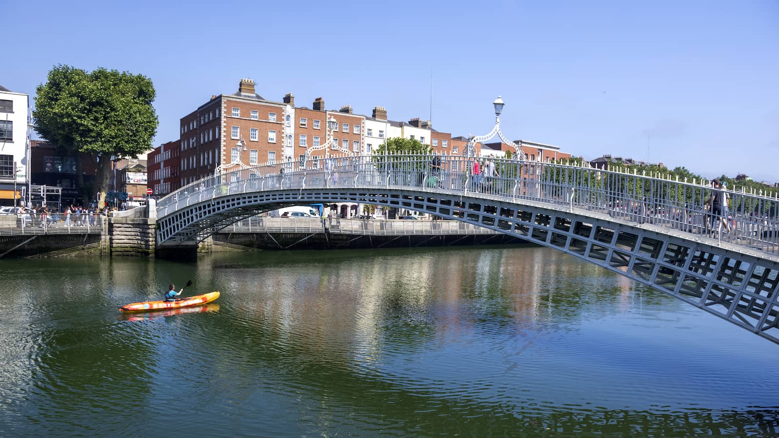 Kayaker paddling under the Ha’penny Bridge on the River Liffey in Dublin city centre.