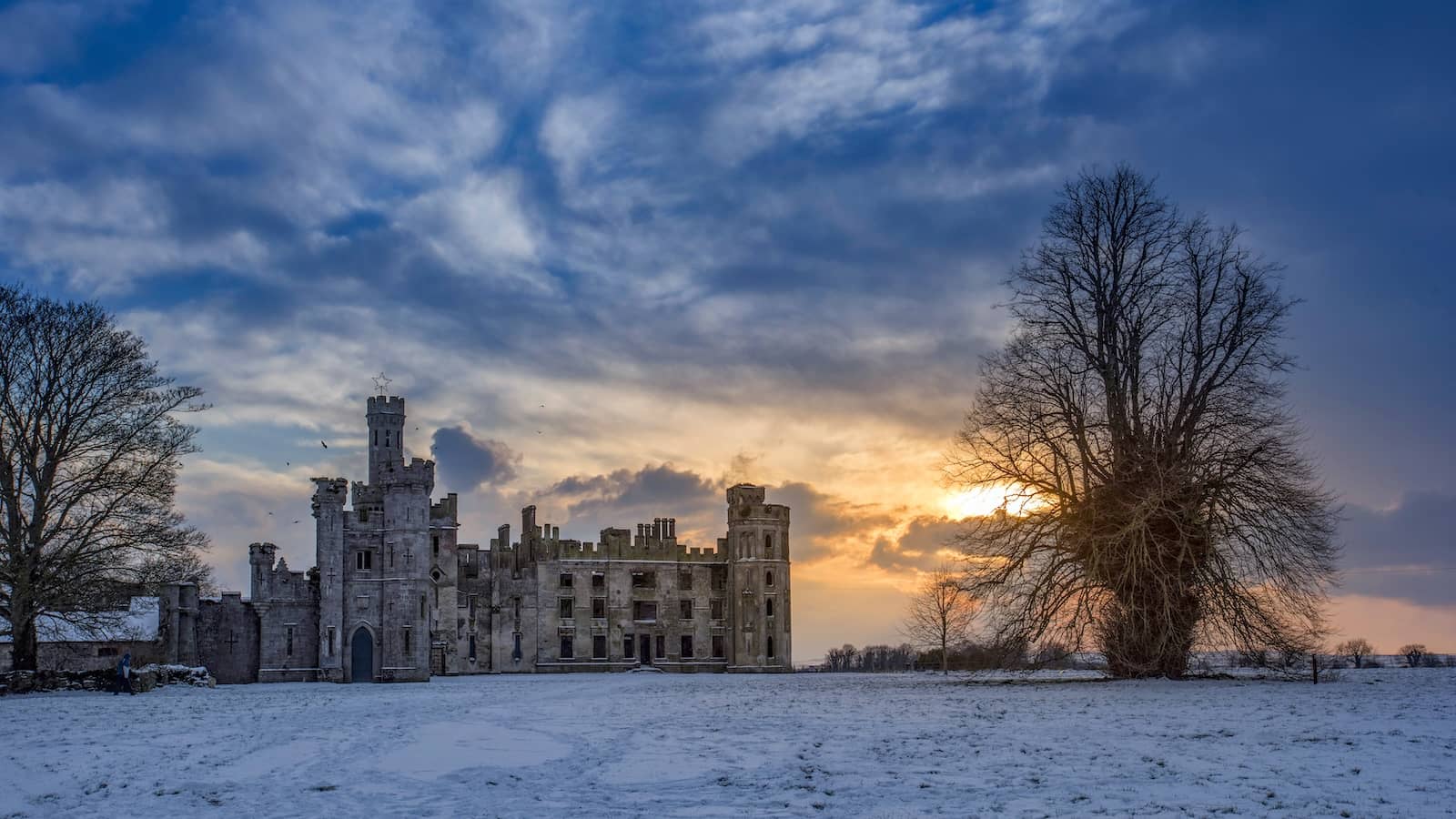 Ducketts Grove in County Carlow at winter sunset, with the gothic ruin set against a dramatic sky and snow-covered grounds.