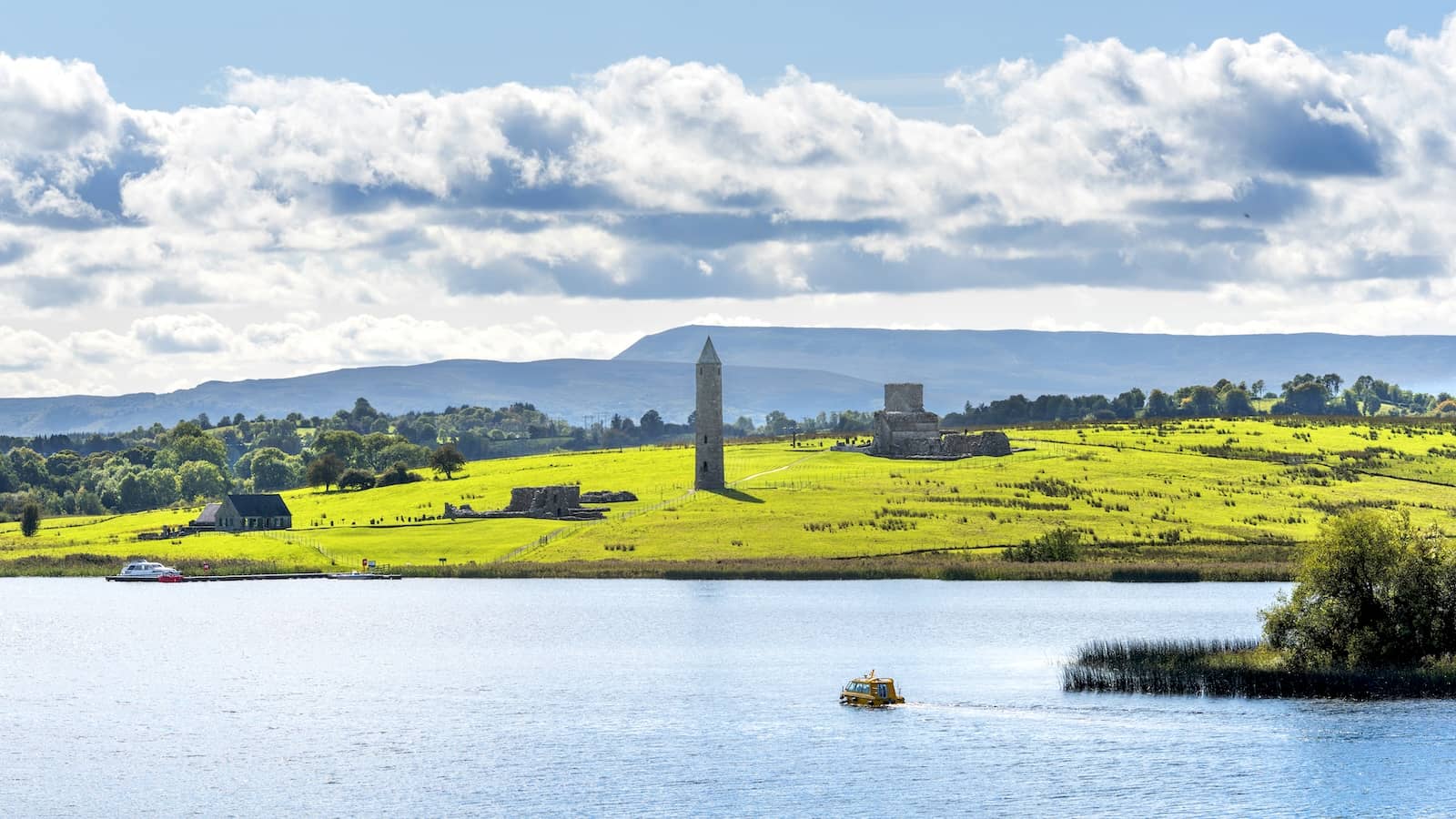 Round tower and monastic ruins on Devenish Island in Lough Erne, County Fermanagh, on a bright summer day.