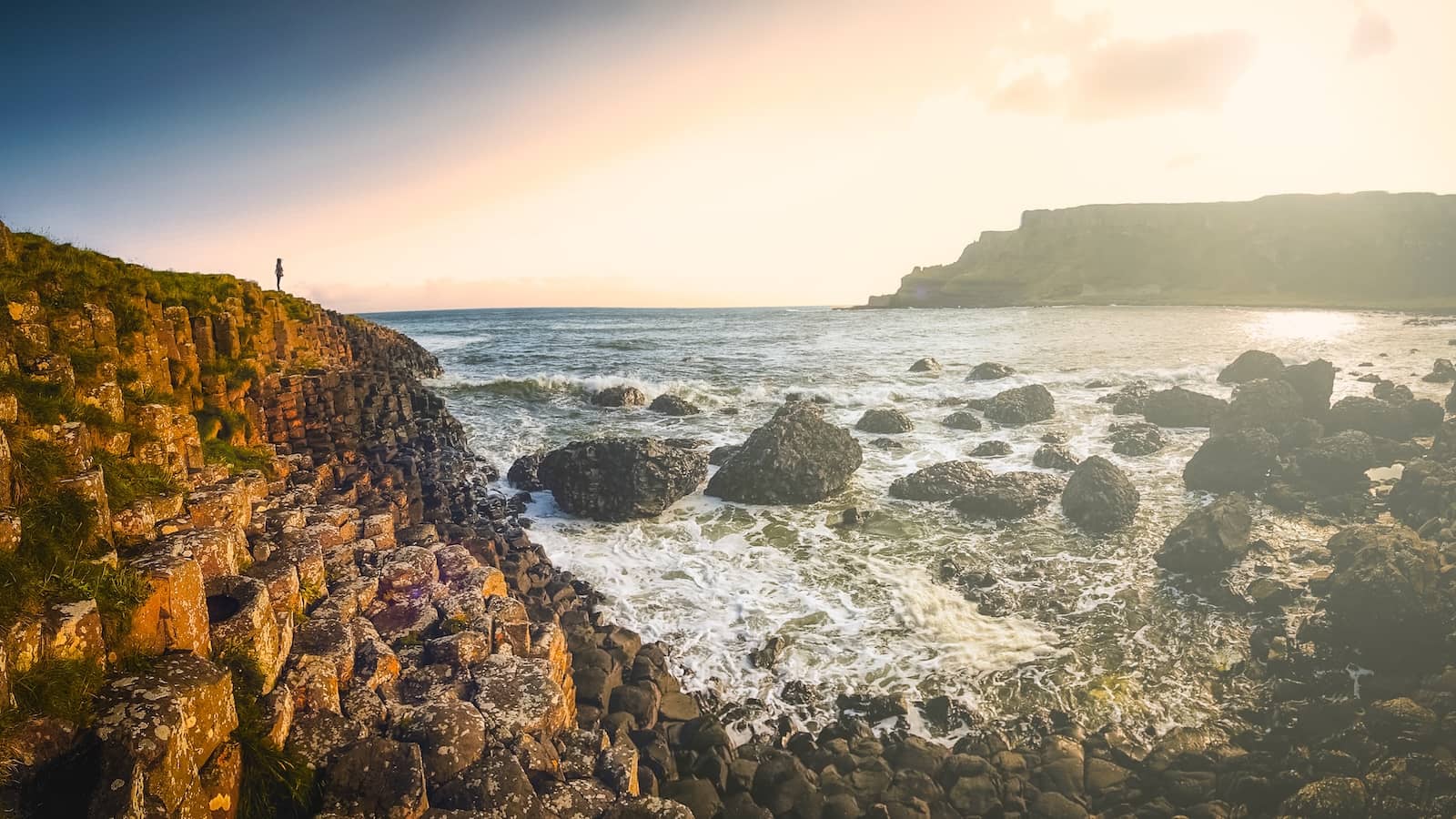 Sunset over the Giant’s Causeway in County Antrim, with hexagonal basalt columns and waves along the rugged coast.