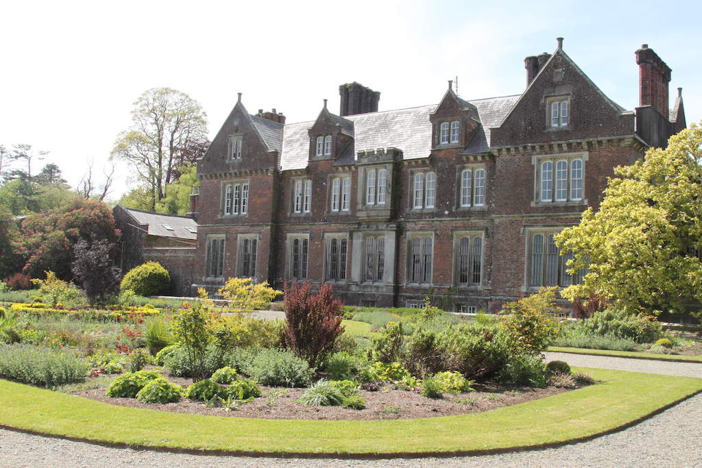 Victorian-style red-brick Wells House with landscaped gardens and bright foliage in County Wexford, Ireland.
