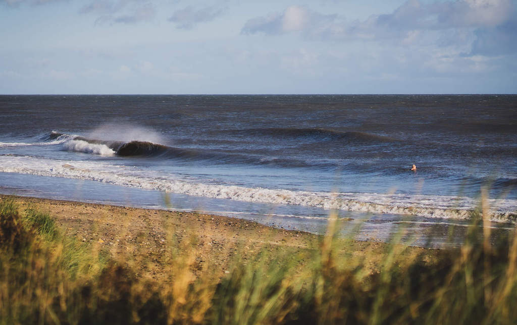 Waves breaking along the sandy shoreline at Brittas Bay, a popular coastal spot in County Wicklow, Ireland.
