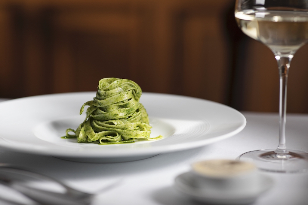 Plate of fresh tagliatelle pasta with green herb sauce served with a glass of wine at Ristorante Rinuccini.