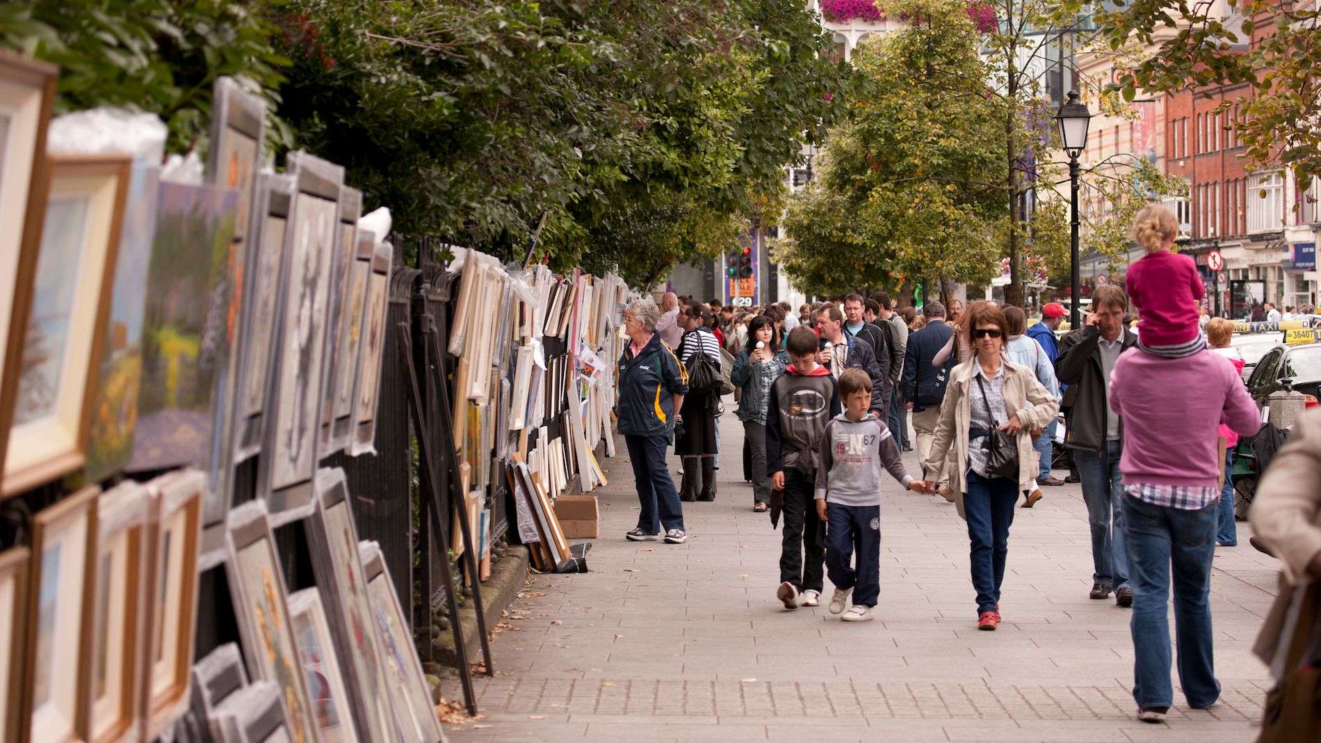 Mensen die kunstwerken bekijken die langs de reling van Merrion Square in Dublin worden tentoongesteld.