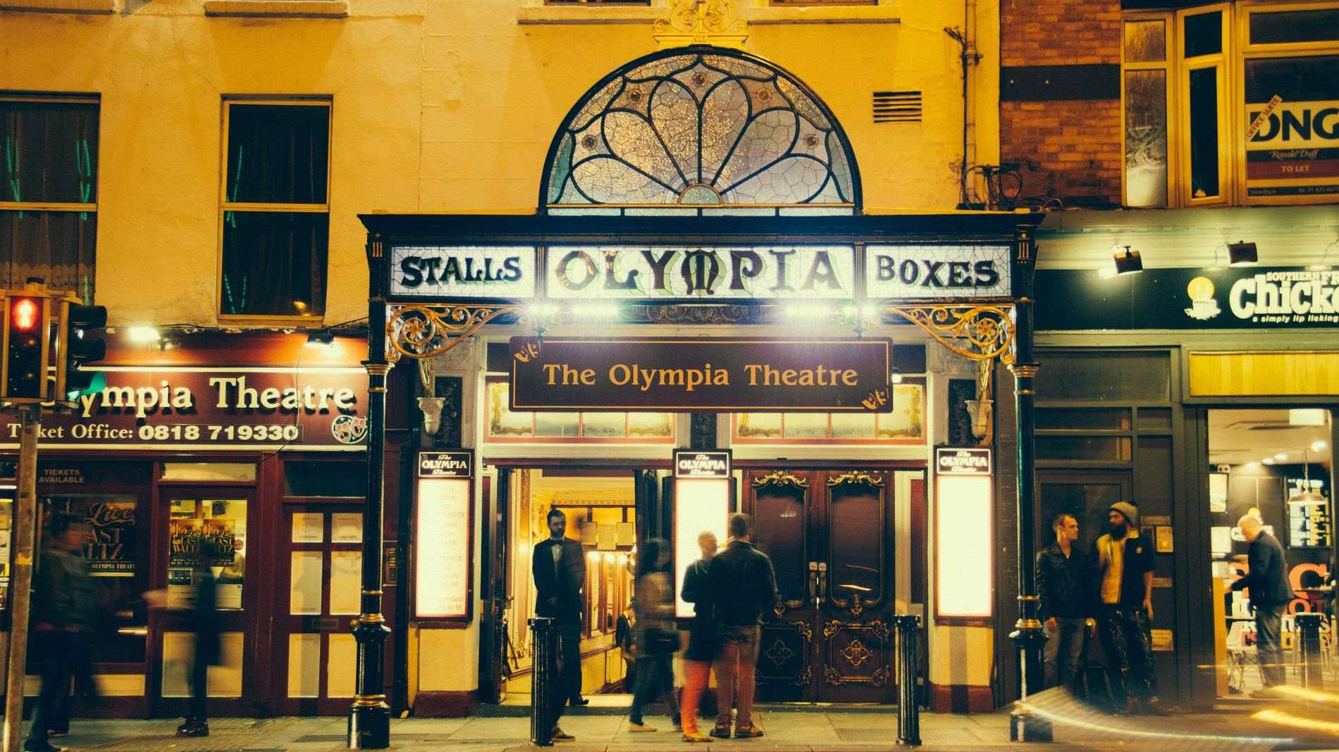 De verlichte gevel van het Olympia Theatre aan Dame Street in Dublin bij nacht.
