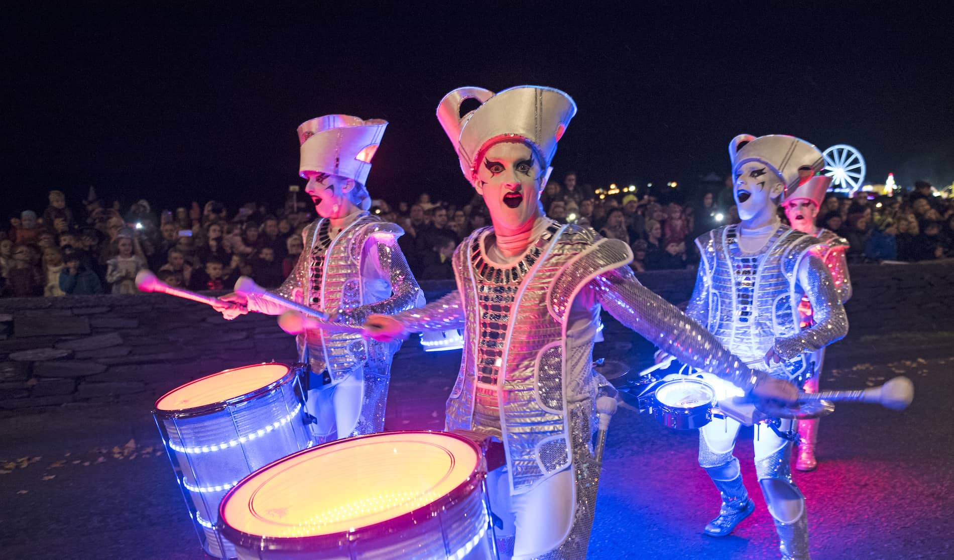 Street performers in silver costumes play drums during Halloween celebrations in Derry~Londonderry.