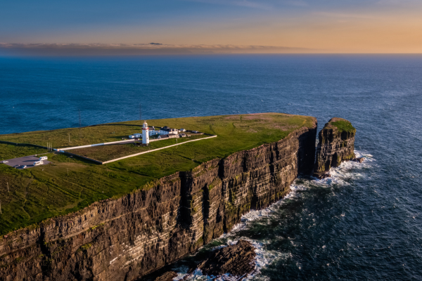A cliff and Irish coastline by sunset