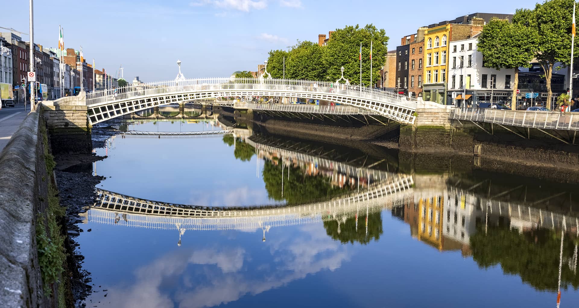 La lumière du soleil matinal se reflète sur le pont Ha'penny Bridge et les bâtiments colorés qui bordent la rivière Liffey à Dublin.