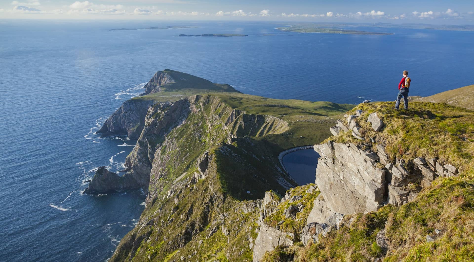 Randonneur surplombant les falaises de Croaghaun et l'océan Atlantique sur l'île d'Achill dans le comté de Mayo, en Irlande.