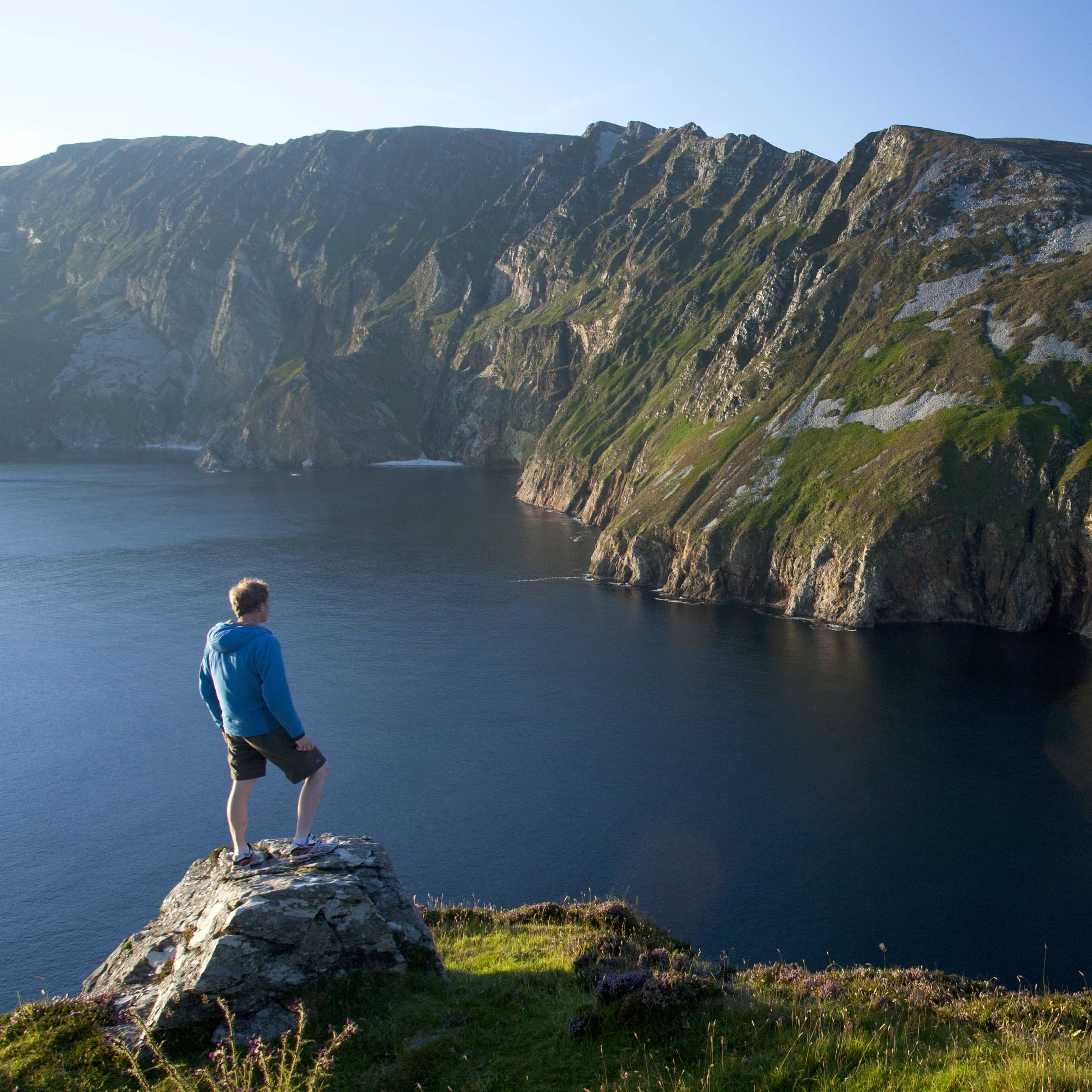 Man standing on viewpoint above the towering Slieve League sea cliffs in County Donegal, Ireland.