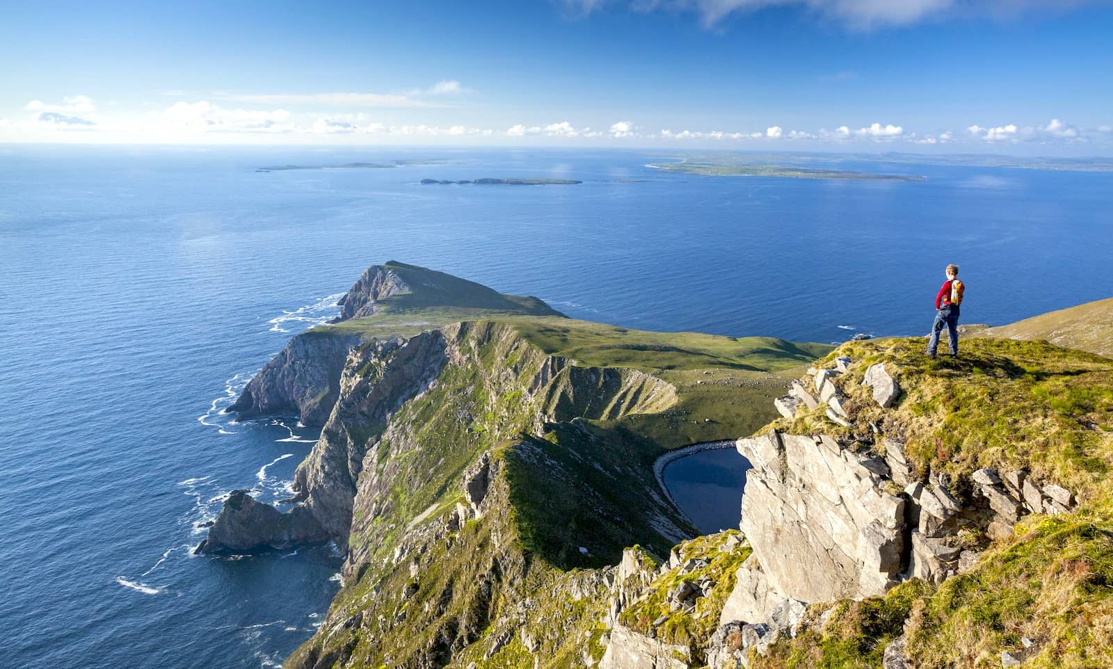 Hiker overlooking Croaghaun Cliffs and Atlantic Ocean on Achill Island, County Mayo, Ireland.
