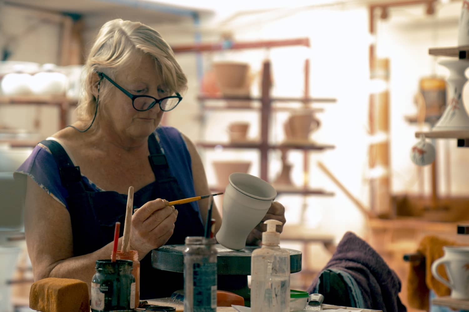 Ceramic artist hand-painting a piece of pottery in her studio in County Kerry.