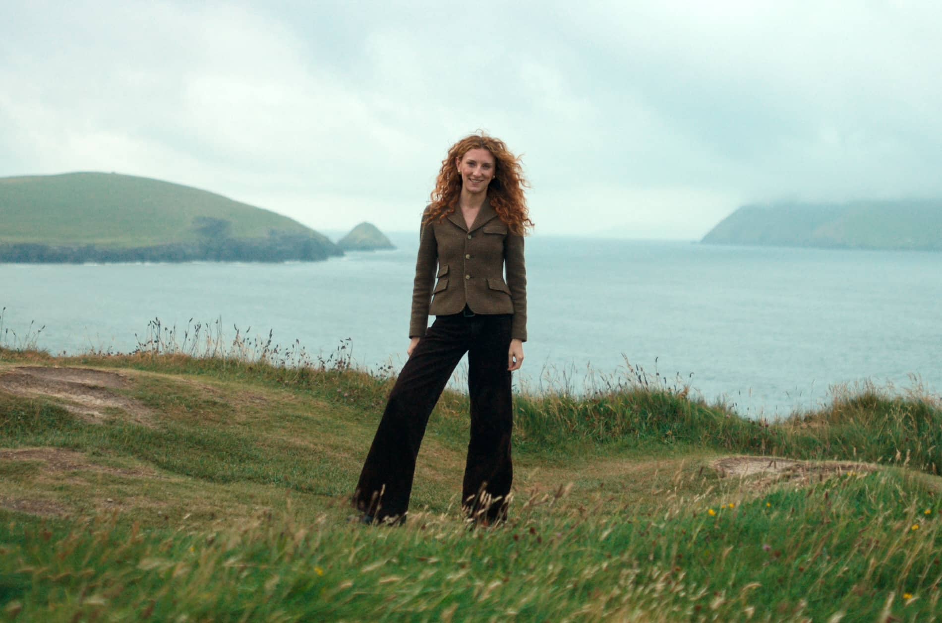 Woman standing on a grassy clifftop overlooking the Atlantic coast in County Kerry.