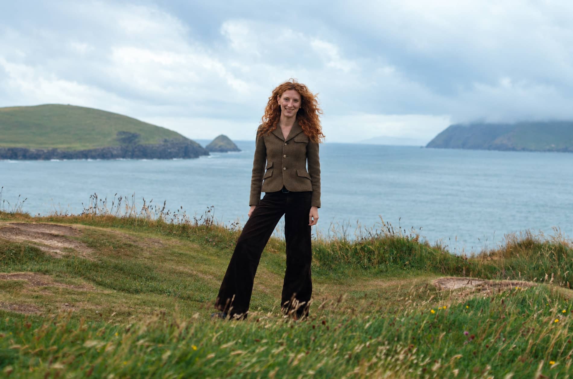 Woman standing on a grassy clifftop overlooking the Atlantic coast in County Kerry.