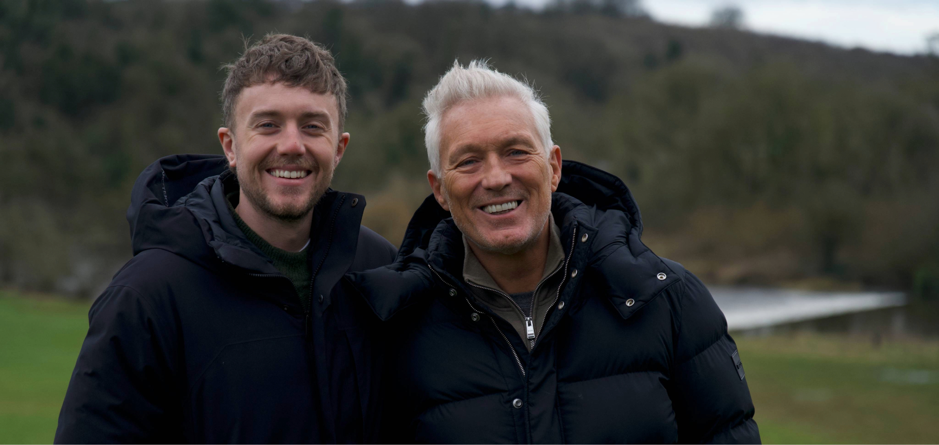 Martin and Roman Kemp smiling beside a forest lake during their Irish road trip.