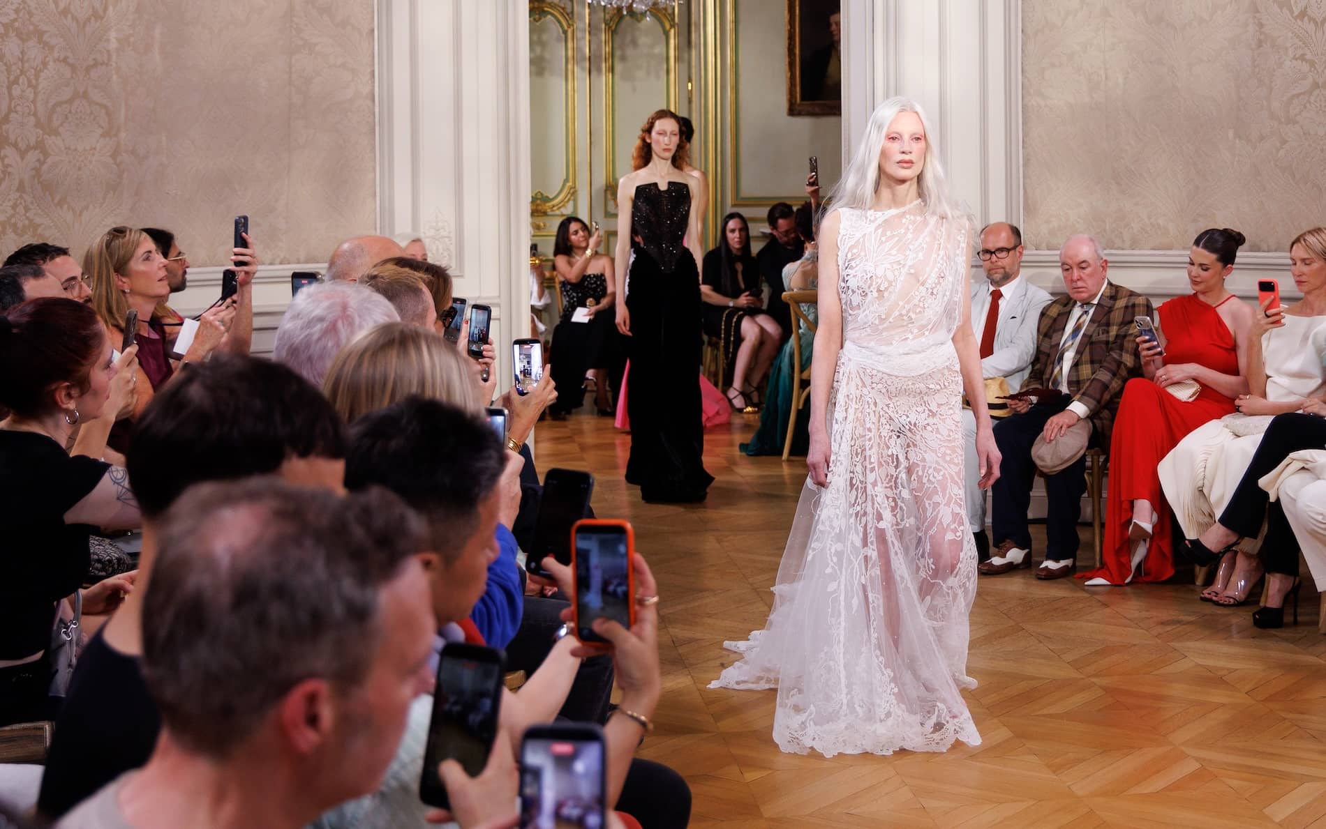 Model wearing an intricate white Carrickmacross lace gown at the Standing Ground fashion show in Paris.