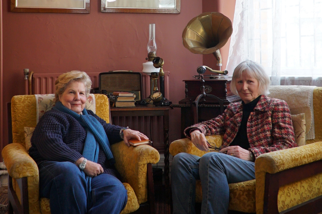 Sandi and the Director of The Yeats Society sit in yellow armchairs beside an antique gramophone, telephone and radio in a cosy room in County Sligo.