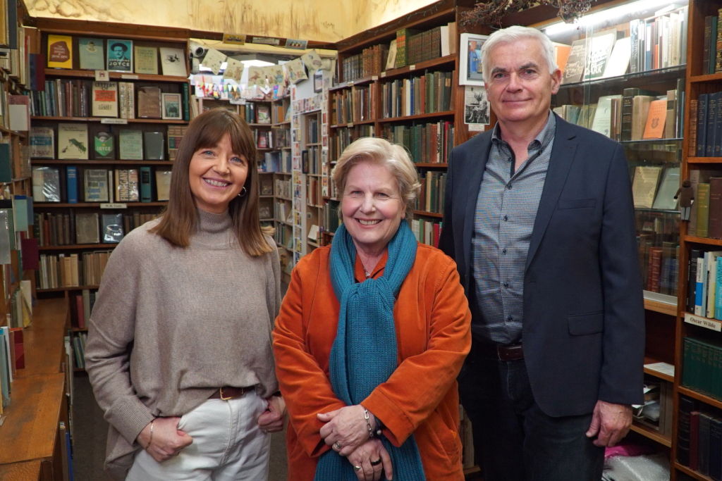 Sandi Toksvig smiling among the bookshelves with the owners at Ulysses Rare Books in Dublin.