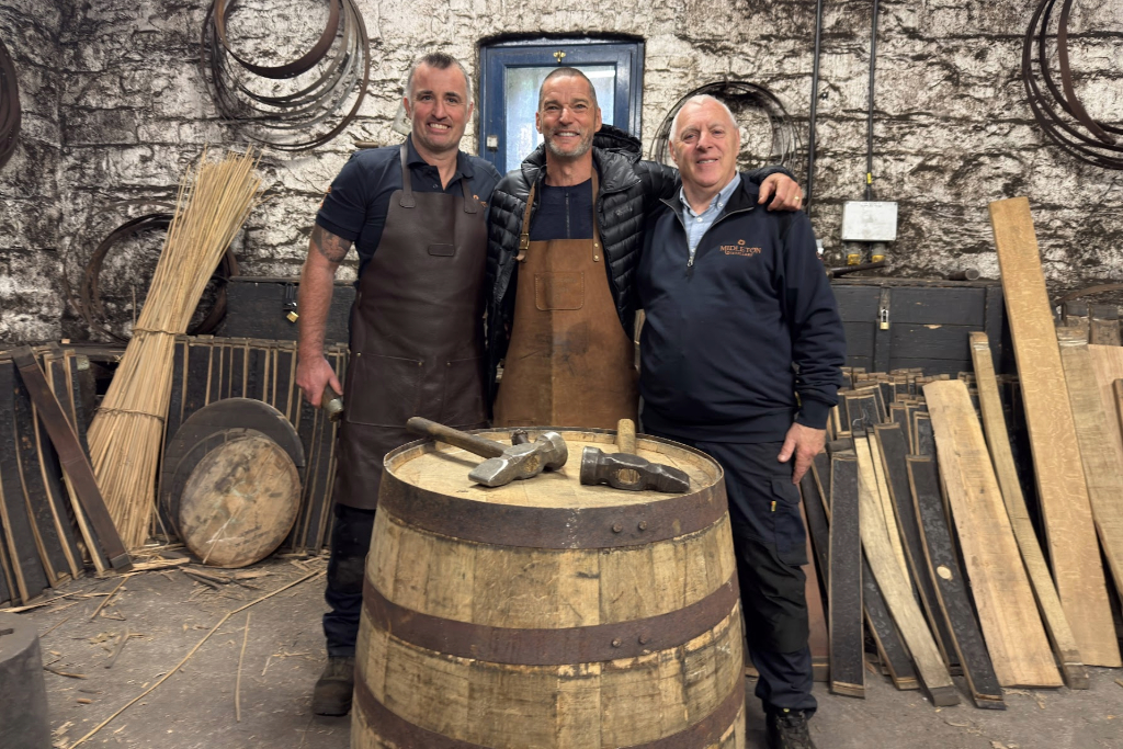 Fred and two workers standing beside a wooden whiskey cask inside Midleton Distillery, County Cork, surrounded by tools.
