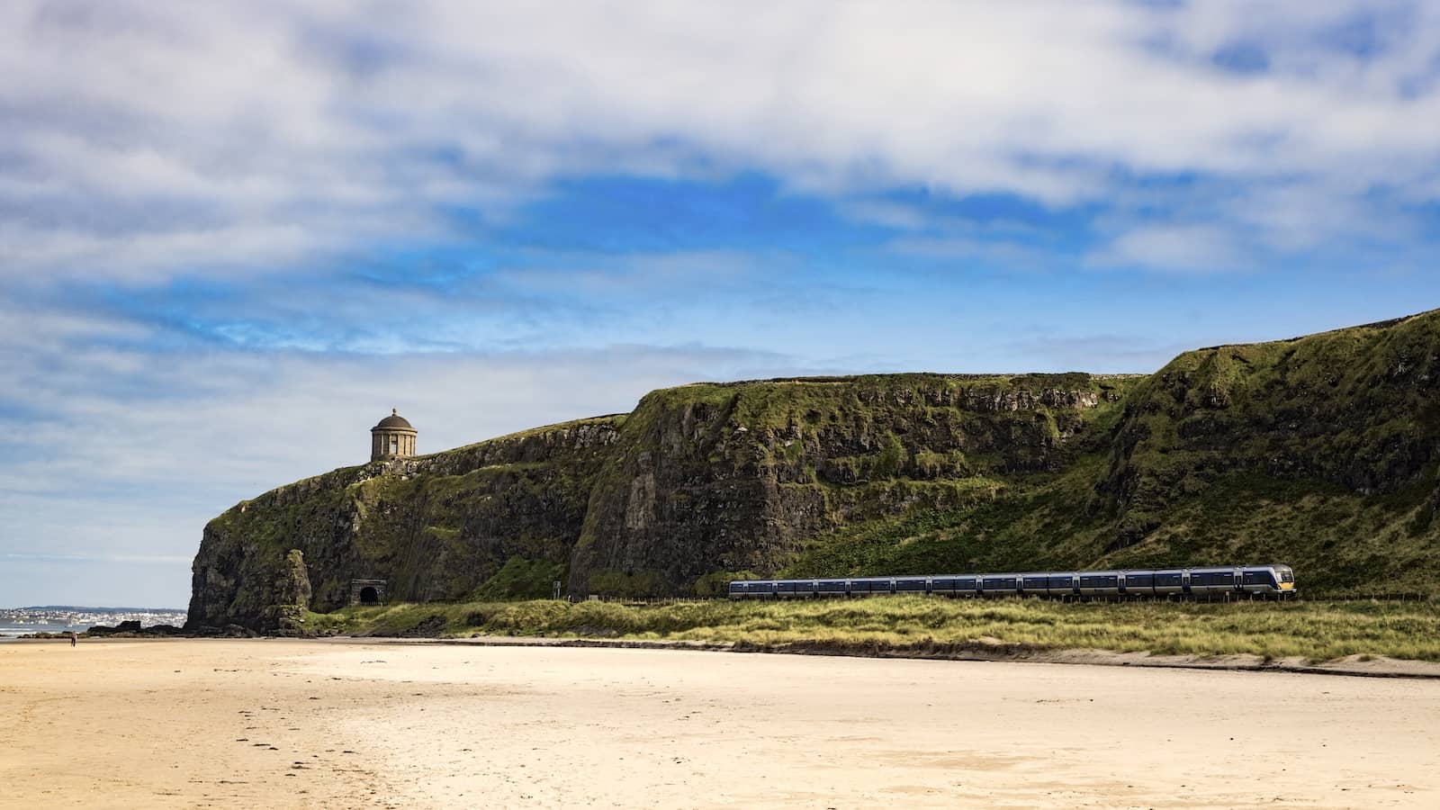 Train travels along Downhill Strand beneath Mussenden Temple on the Causeway Coast, County Londonderry.