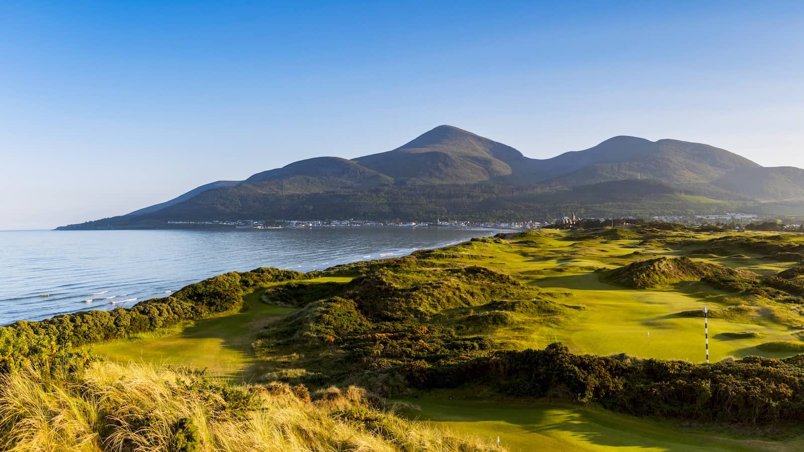 Royal County Down golf course stretches along the coast with the Mourne Mountains beyond, Newcastle, County Down.