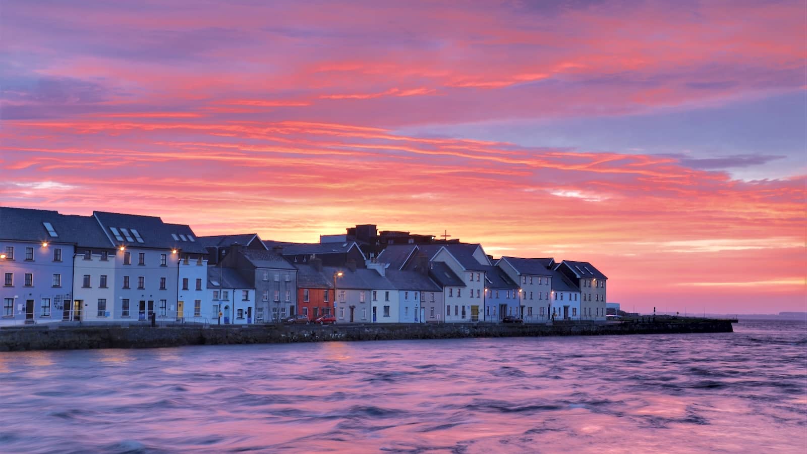 Colourful houses line the waterfront at sunset in the Claddagh, Galway city.