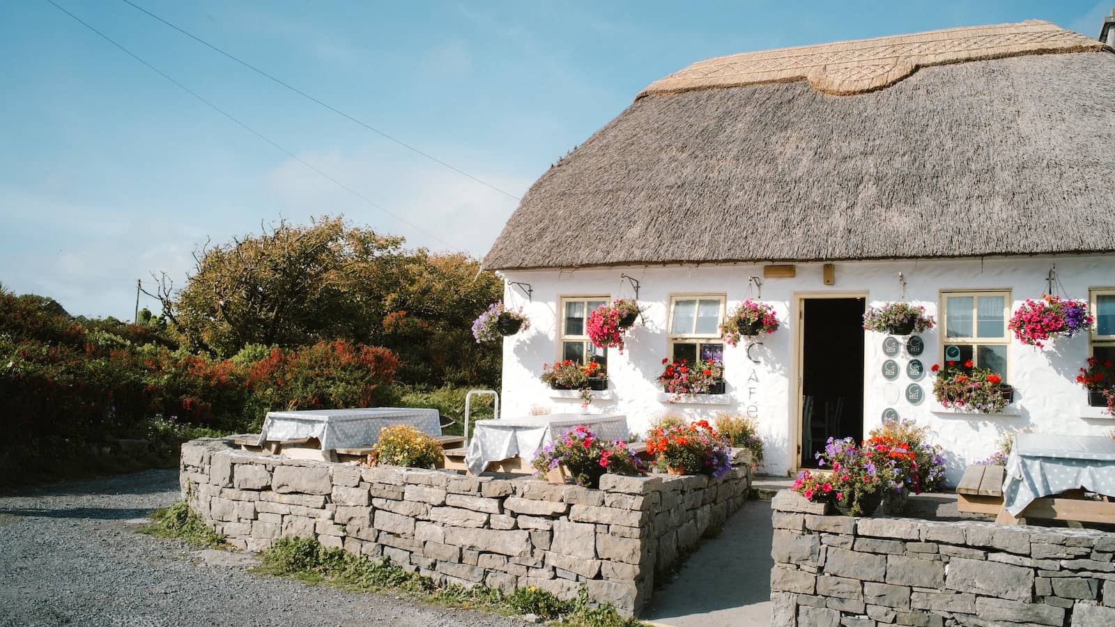 Thatched cottage with bright flowers and stone walls on the Aran Islands, County Galway.