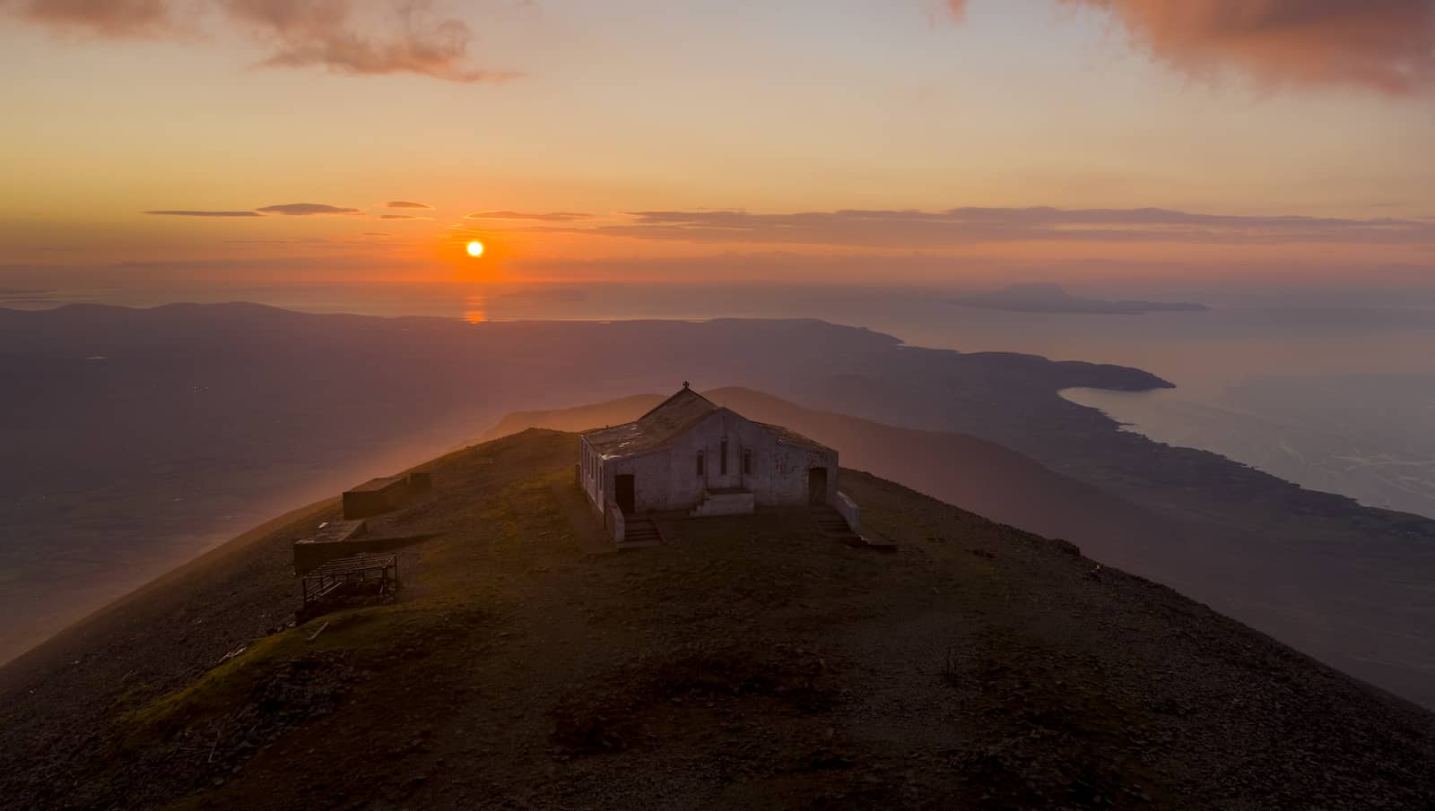 Hilltop chapel at sunset with sweeping views over coastline and islands, Croagh Patrick, County Mayo.