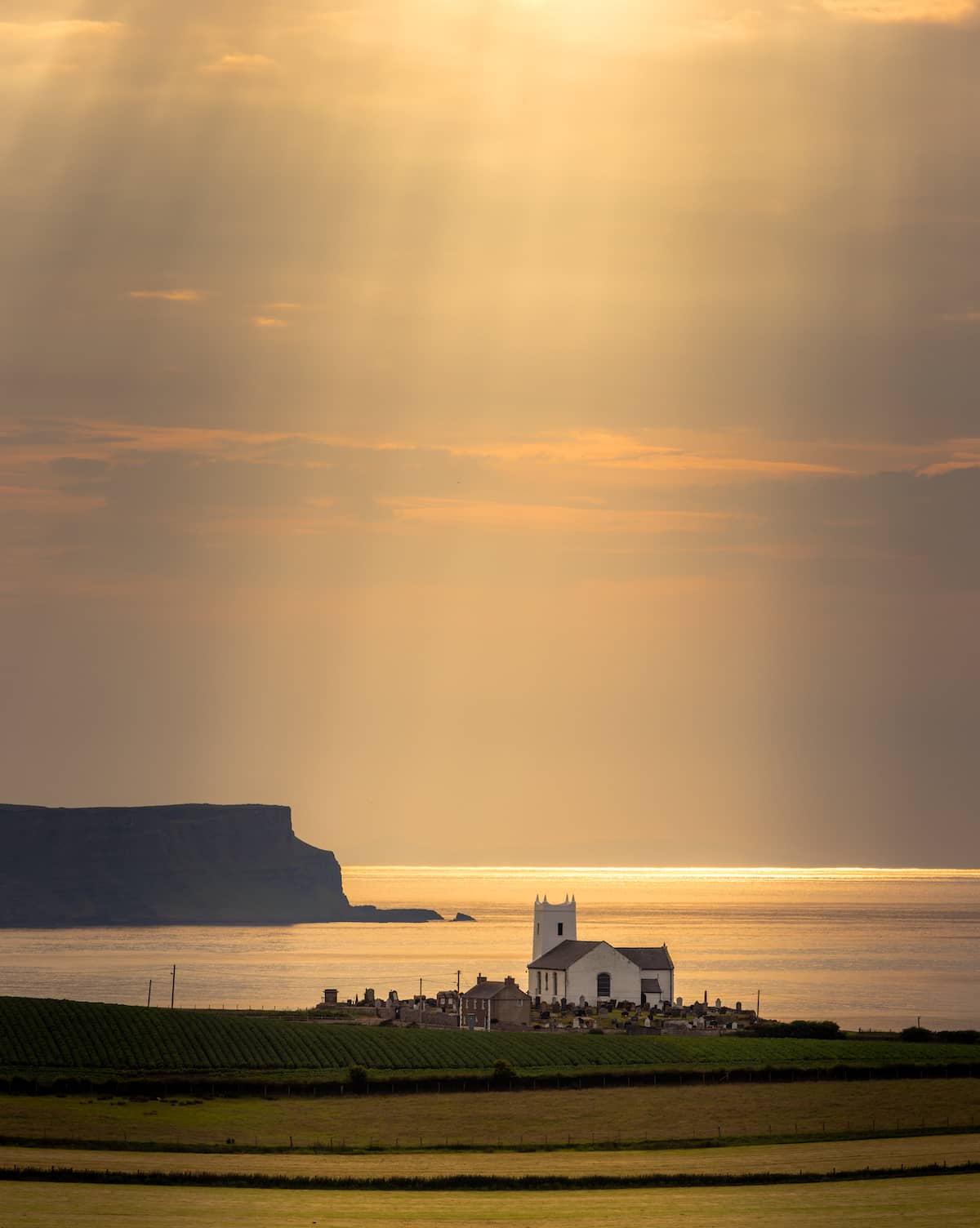 Ballintoy Church overlooking the Atlantic Ocean at sunset on the Causeway Coast, County Antrim.