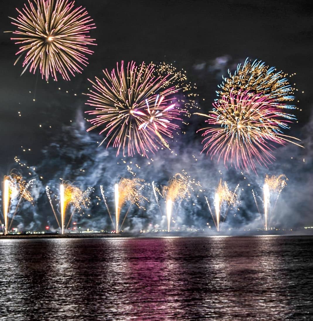 Vuurwerk boven Dublin Bay dat 's nachts kleurrijk licht weerkaatst op het kalme water.