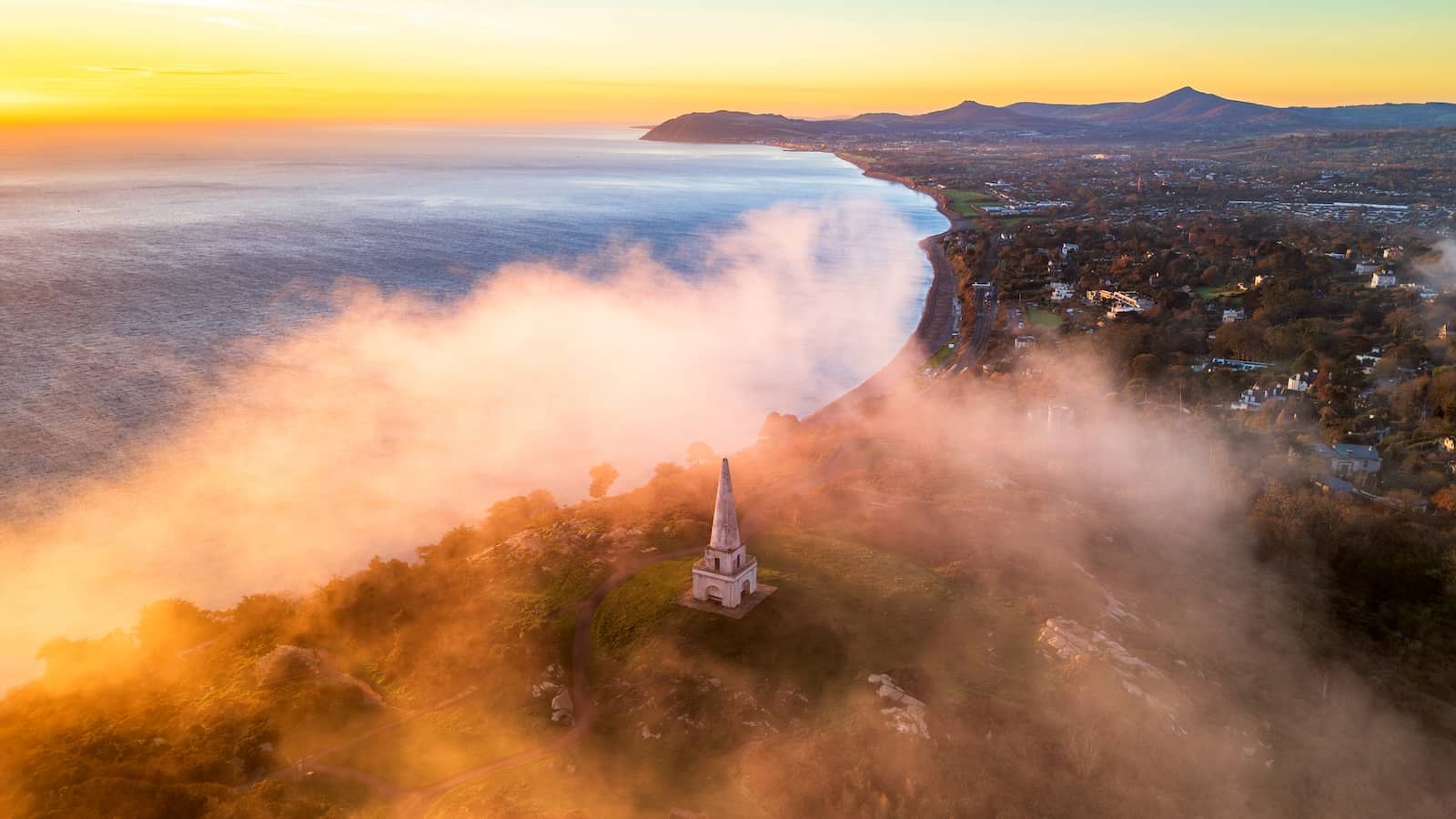 Mist boven Killiney Hill en de obelisk bij zonsopgang met uitzicht op Dublin Bay en de Wicklow Mountains.