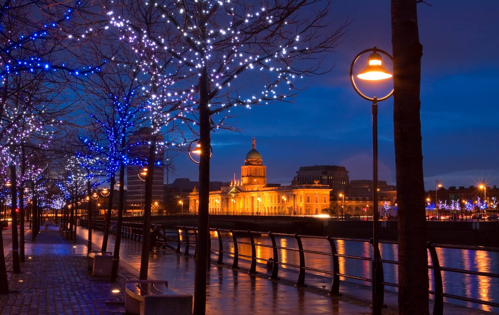  Avondzicht op het Custom House van Dublin, verlicht naast de rivier de Liffey, met feestelijke verlichting langs de kades.