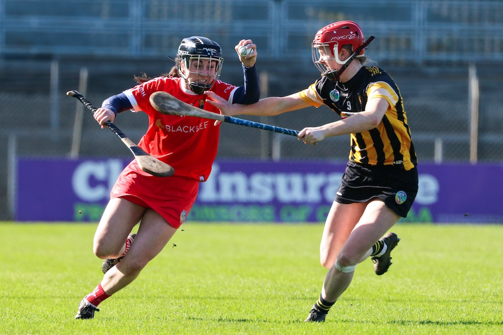 Een spannende camogiewedstrijd met spelers in rood en zwart-goud gekleurde shirts die strijden om de sliotar.