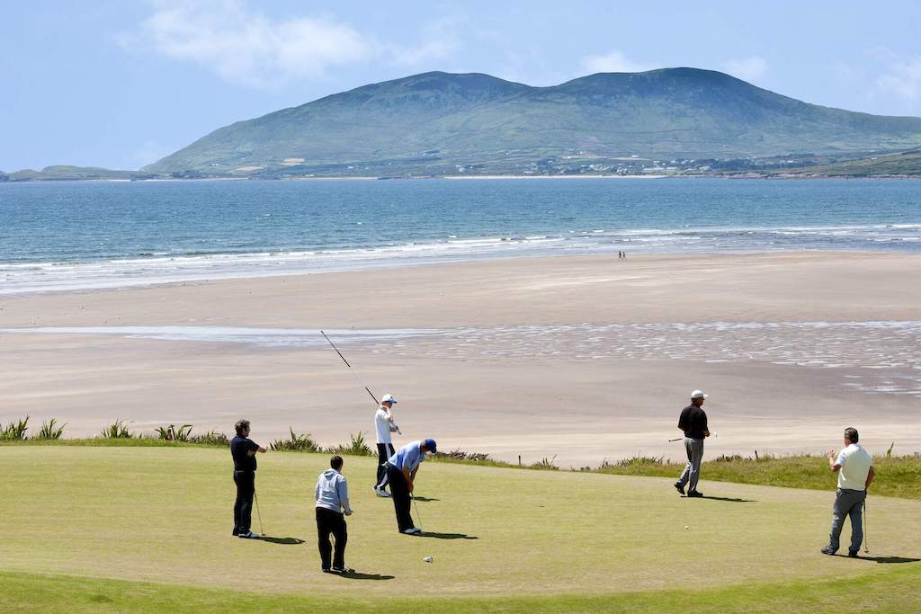 Golfer spielen am Ufer des Waterville Golf Links mit dem Atlantischen Ozean und den Bergen in der Ferne.