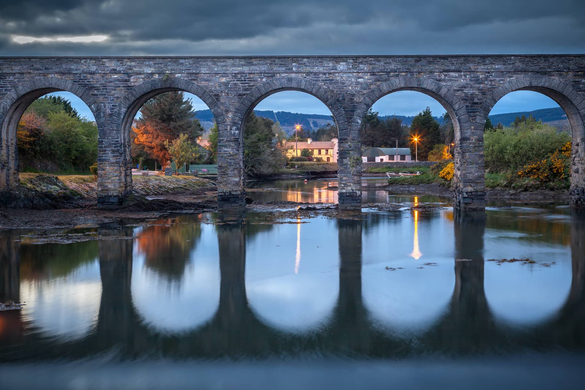 Il viadotto di pietra si riflette nelle acque tranquille durante il crepuscolo a Ballydehob, nella contea di Cork.