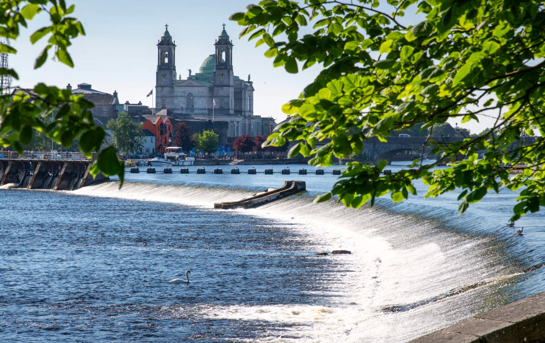 Rivier Shannon stuwdam met de kerk van Athlone en kleurrijke stadsgebouwen op de achtergrond.