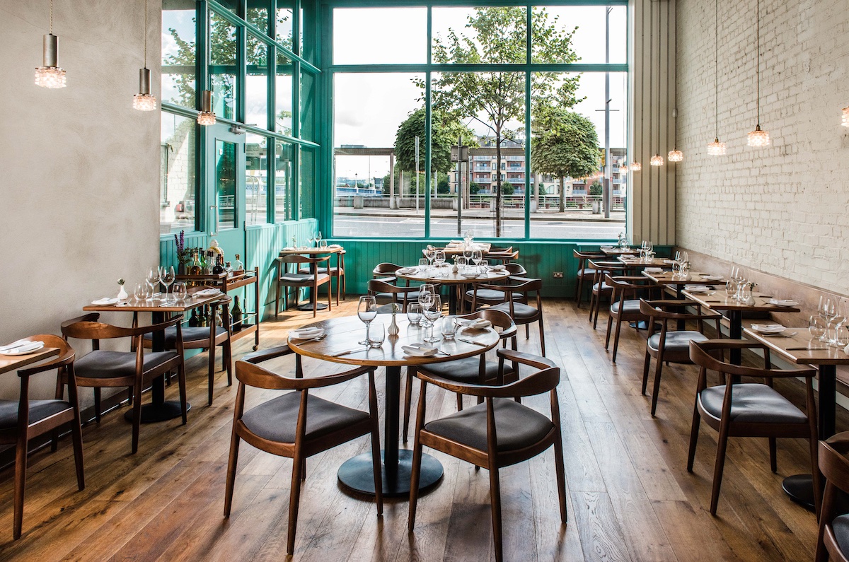 Bright restaurant interior with wooden floors and large windows at OX restaurant, Belfast.