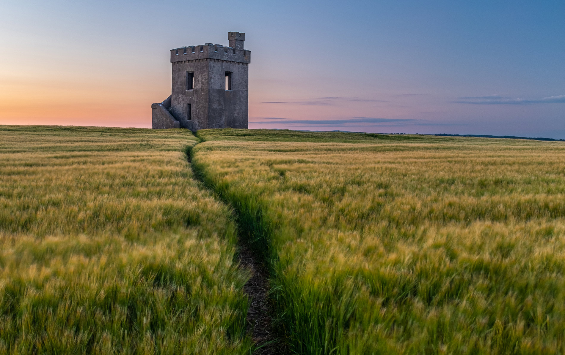 Stone tower in a coastal barley field at sunset, County Waterford.