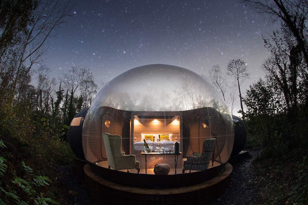 Alojamiento en una cúpula de burbuja transparente iluminada desde el interior bajo un cielo lleno de estrellas en el condado de Fermanagh.