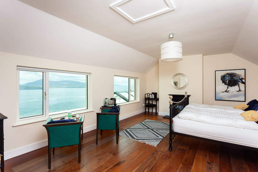 Dormitorio costero luminoso con suelos de madera y vistas al mar a través de la bahía en la isla de Clare, Mayo.