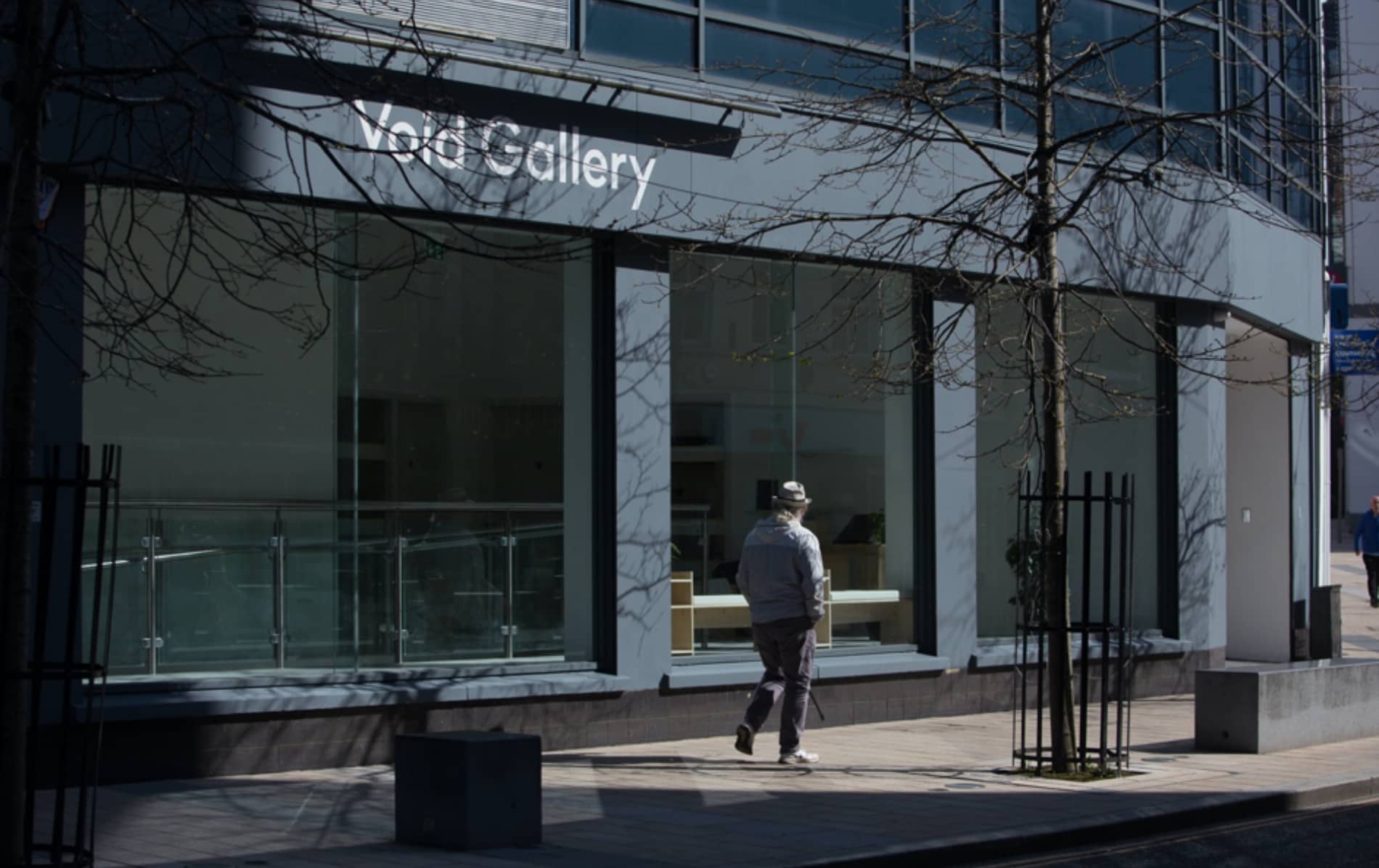 Modern glass-fronted Void Gallery with passerby outside on a quiet street in central Derry~Londonderry.