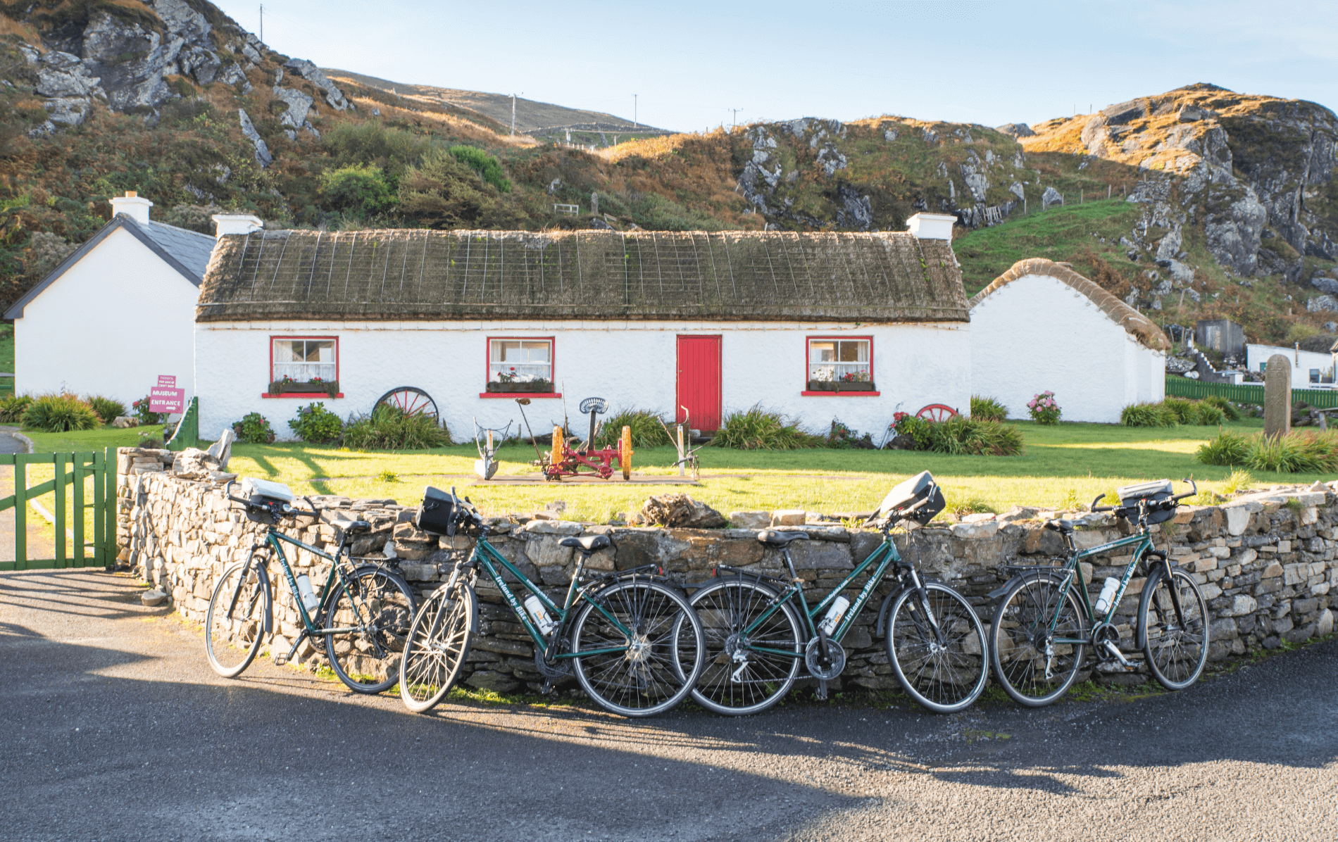 Whitewashed thatched cottage with red door and bicycles in Glencolmcille Folk Village, Donegal.