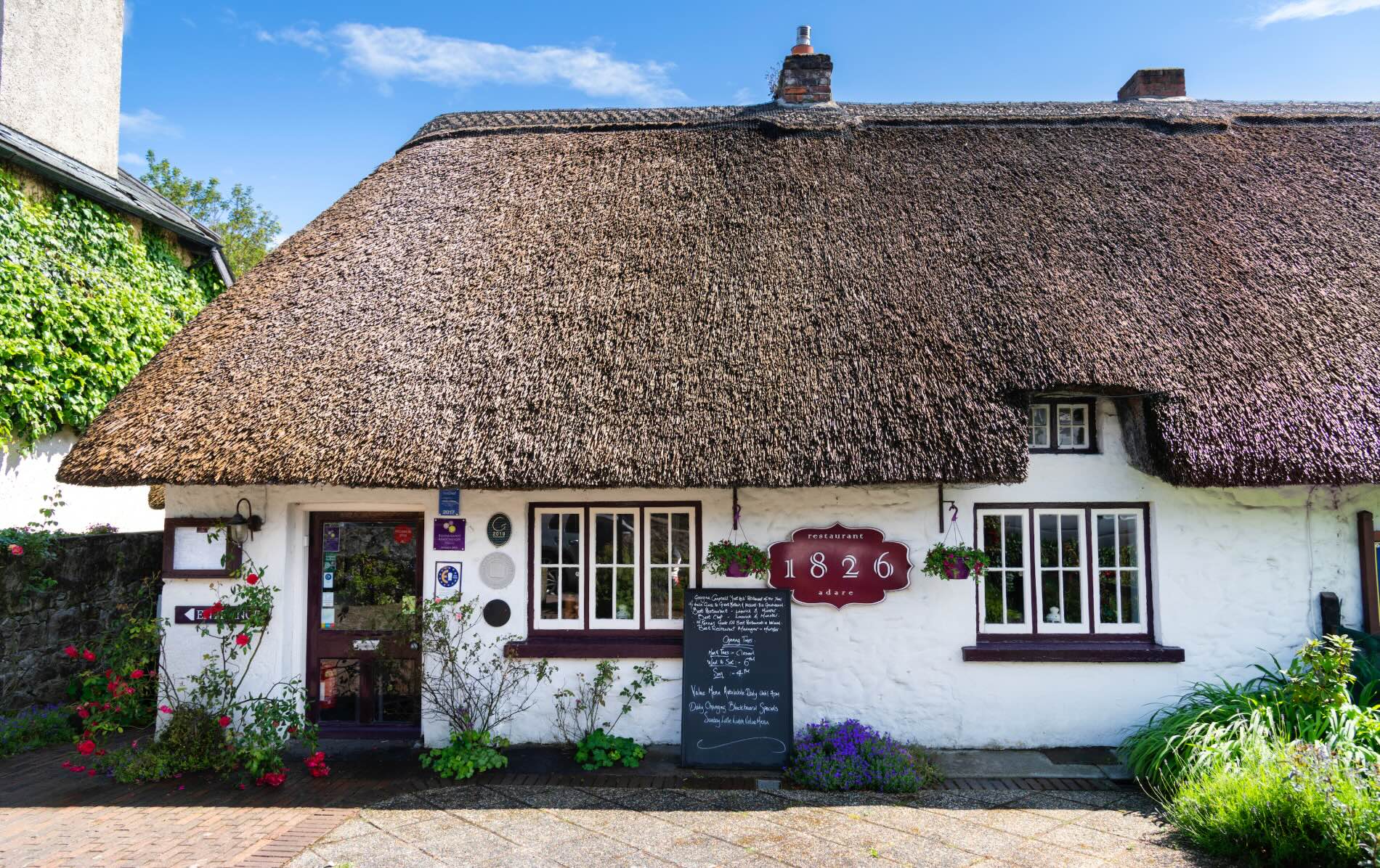1826 Adare restaurant with thatched roof, hanging baskets and menu board in Adare, County Limerick.