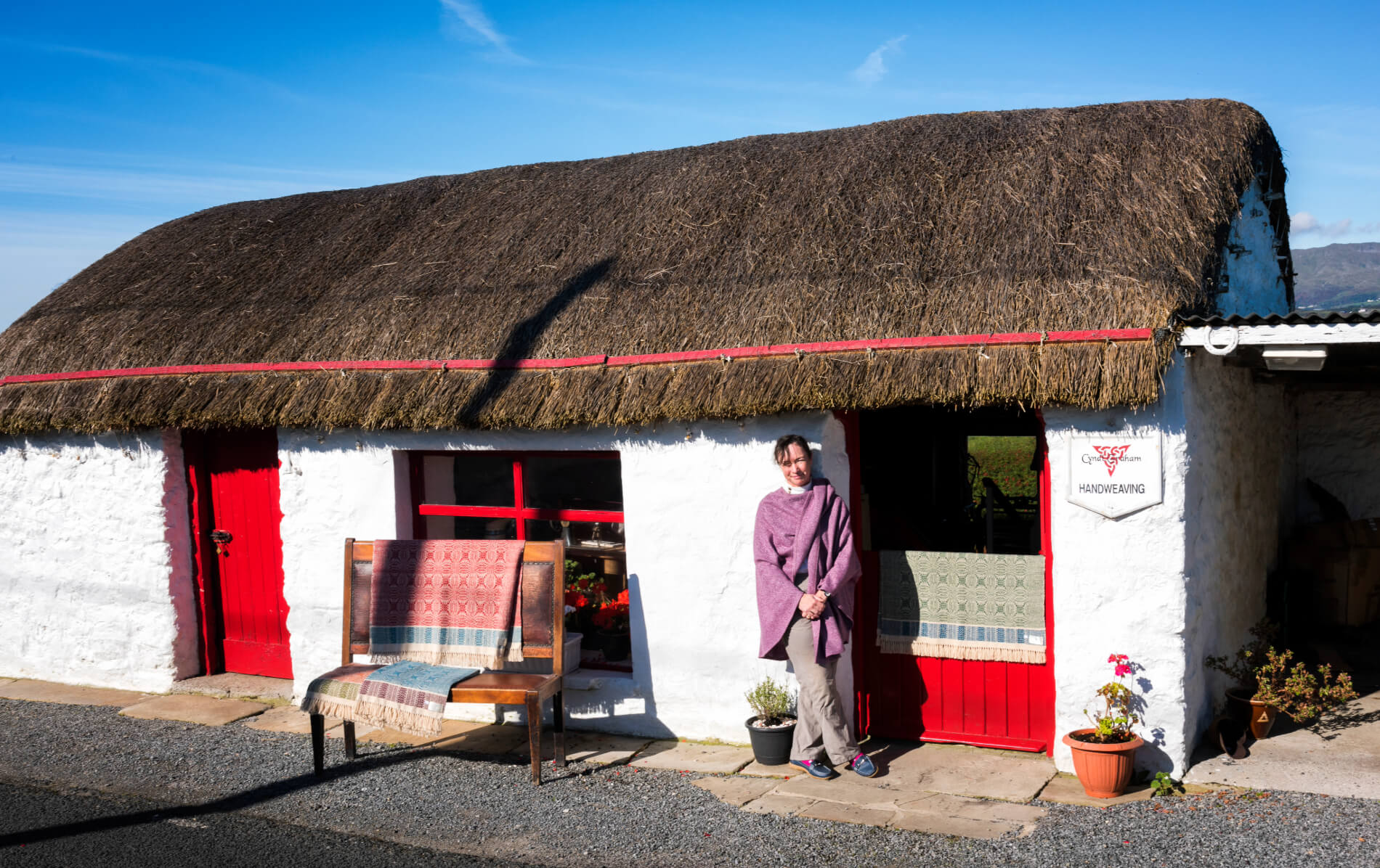 Whitewashed thatched cottage with red door and windows at Cyndi Graham Handweaving, Galway.