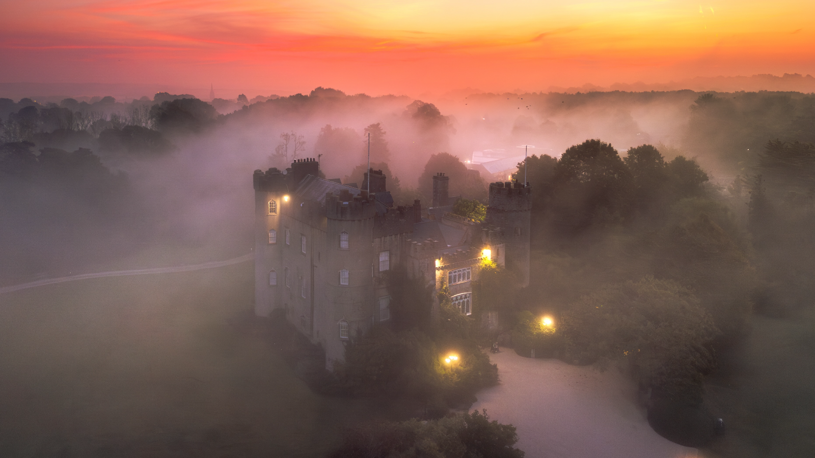Malahide Castle illuminated at dawn through mist in Malahide, County Dublin.